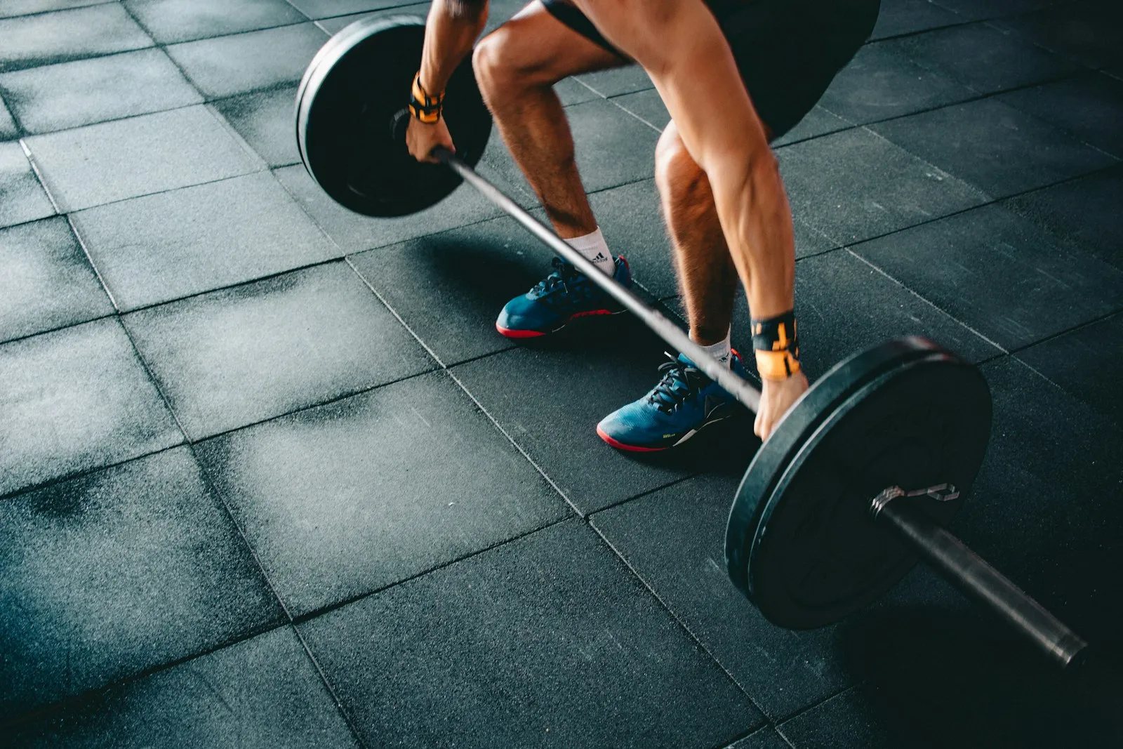 Setting up to a loaded barbell on a dark gym floor.