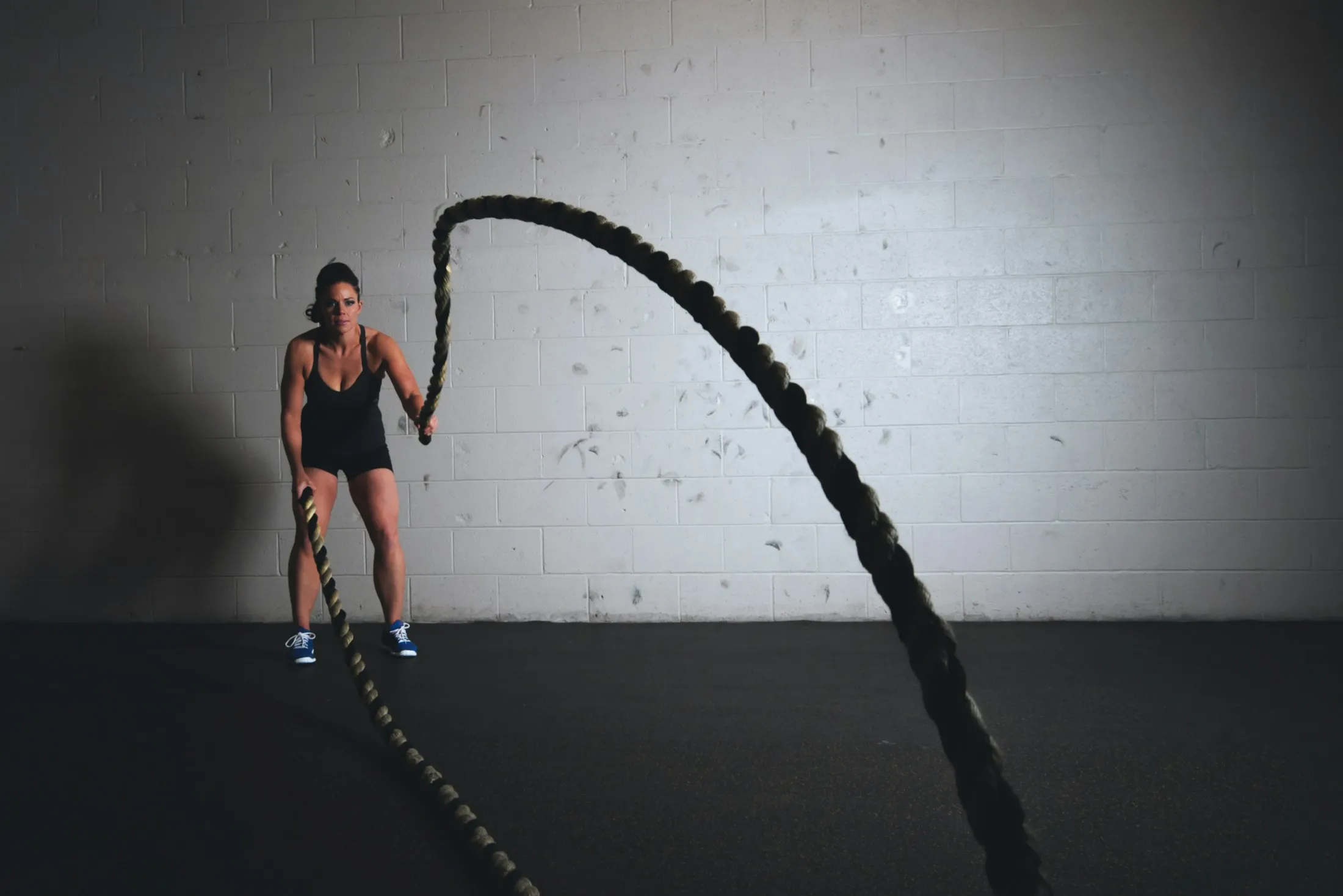 Battle ropes mid-swing in a dark gym.