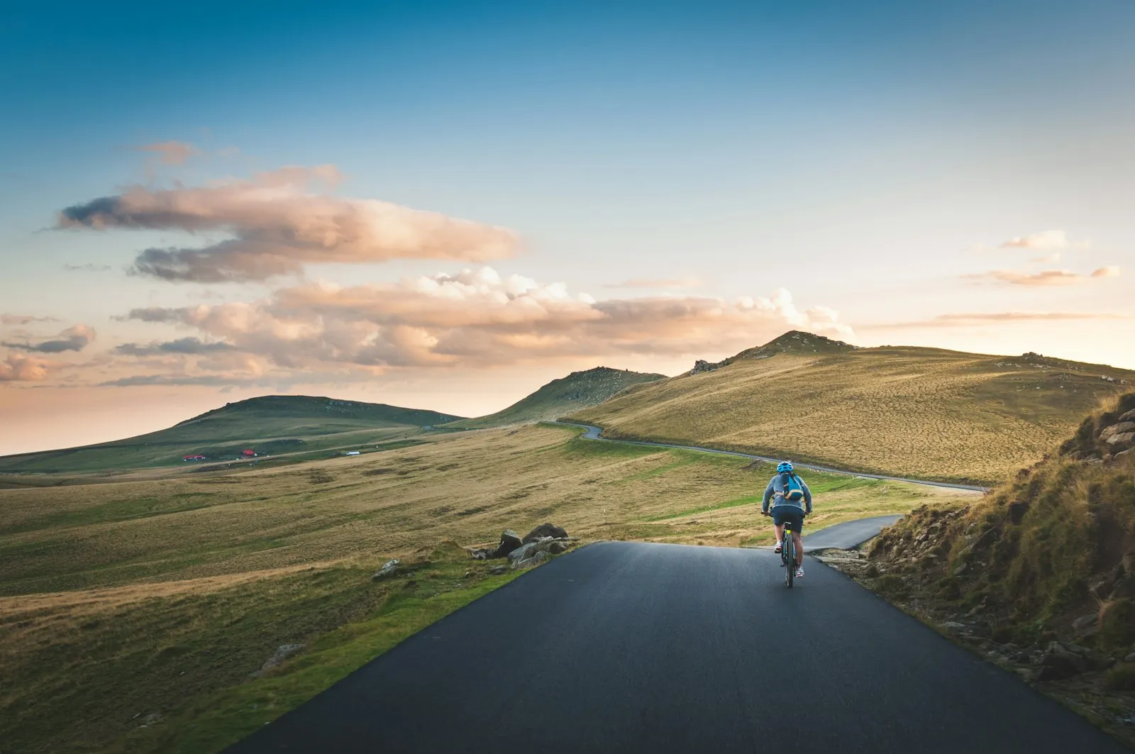 A lone cyclist climbing a mountain road at golden hour.