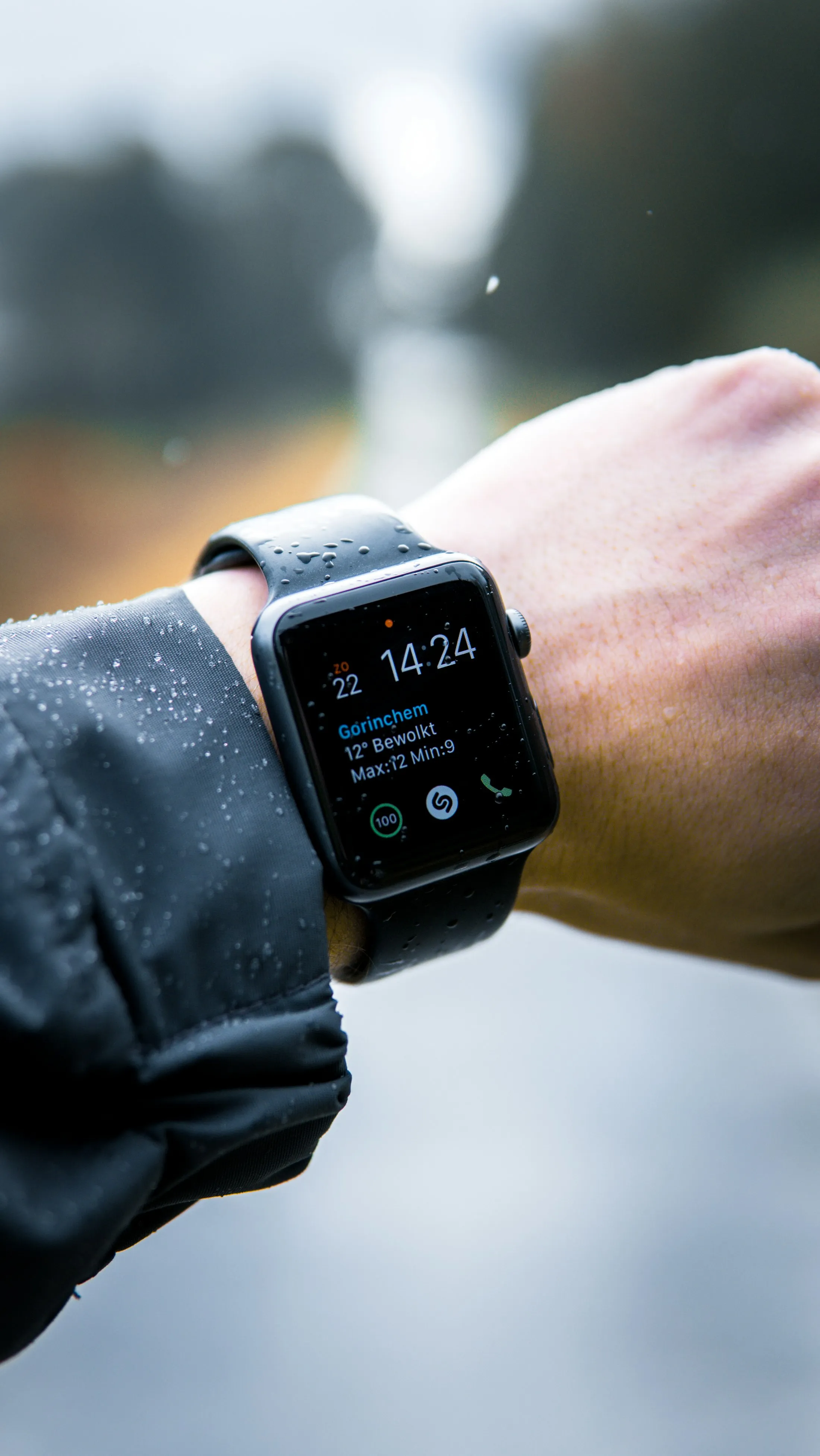 An Apple Watch on a wrist mid-run, rain on the strap.